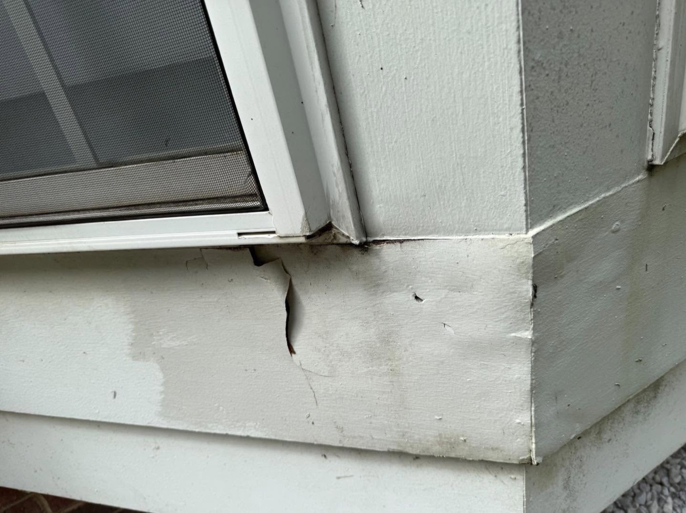 Close-up of cracked and rotted trim under the window